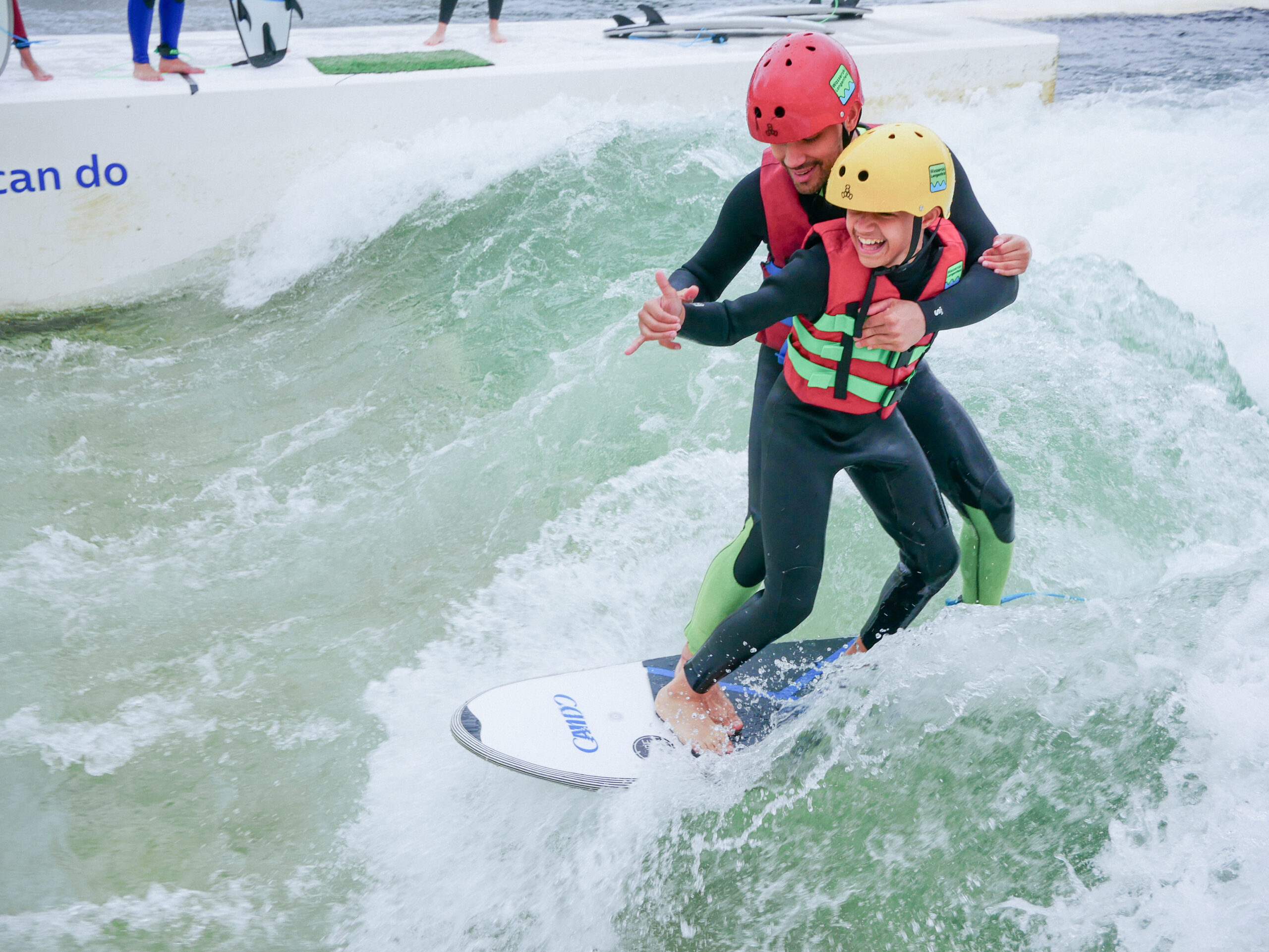 Kids helping each other while learning how to surf